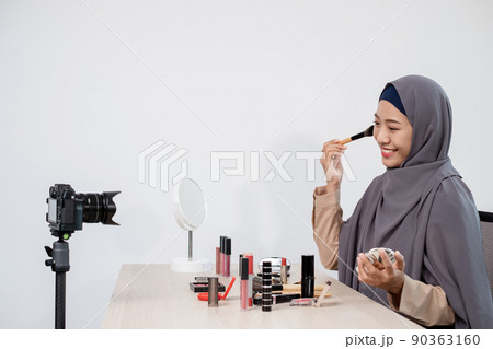 Muslim women making video beauty vlogger bloggers doing a cosmetic makeup tutorial vlog with brushes looking camera Save clips and share them on social media live via the internet Online 90363160