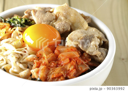もやしナムルやキムチ、豚肉など沢山の具材が入っているビビンバ丼 90363992