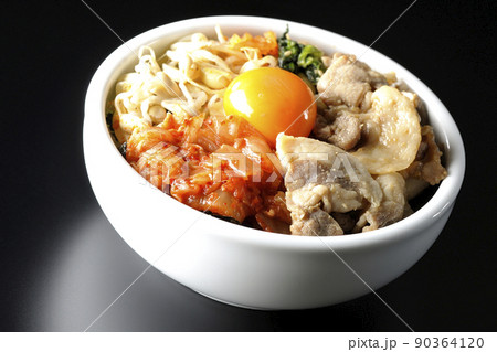 もやしナムルやキムチ、豚肉など沢山の具材が入っているビビンバ丼を黒背景で撮影 90364120