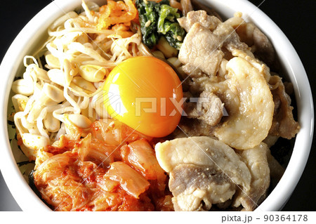 もやしナムルやキムチ、豚肉など沢山の具材が入っているビビンバ丼を黒背景で俯瞰撮影 90364178