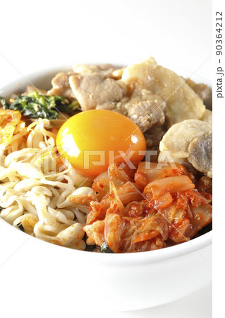 もやしナムルやキムチ、豚肉など沢山の具材が入っているビビンバ丼を白背景で撮影 90364212