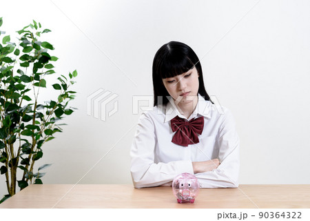 豚の貯金箱を前に悩む女子高校生 色暗め 豚の貯金箱を前に悩む女子高校生 色暗め 90364322