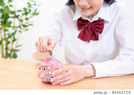 豚の貯金箱に楽しそうに貯金をする女子高校生 豚の貯金箱に楽しそうに貯金をする女子高校生 90364720