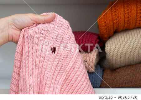 Hand holding woolen knitted cloth with hole 90365720