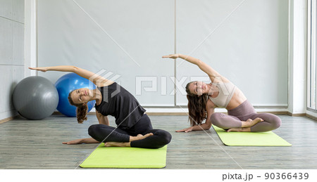 Two young women play yoga stretching, exercise for health in fitness, the concept of physical and mental health care 90366439