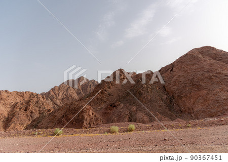 A road next to a mountainous desert landscape. Road 12 on the way to Eilat, Israel, on the Egyptian border. Mountains in different and varied sand colors. A road next to a mountainous desert landscape. Road 12 on the way to Eilat, Israel, on the Egyptian border. Mountains in different and varied sand colors. 90367451