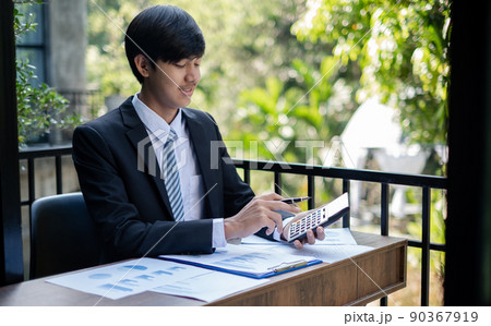 Young Asian businessman financial market analyst sits at their desks and calculate financial graphs showing the results of their investments planning the process of successful business growth 90367919