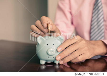 The hand of a businessman puts coins in a piggy bank, saves money with coins, steps into a successful growth business, and saves for retirement concept The hand of a businessman puts coins in a piggy bank, saves money with coins, steps into a successful growth business, and saves for retirement concept 90368691