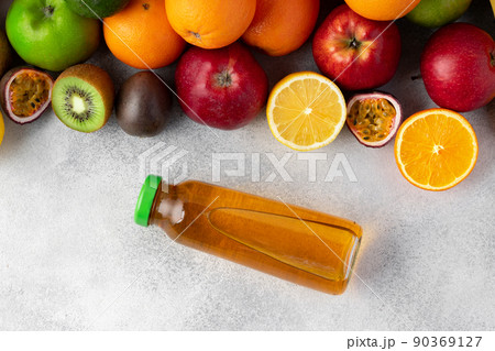 Various fruits and freshly squeezed fruits juice in bottle on gray background Various fruits and freshly squeezed fruits juice in bottle on gray background 90369127