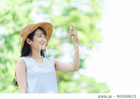 日焼け止め・虫除けスプレーする女性（笑顔・顔） 90369615