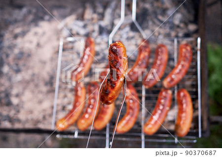 Tasty Sausages grilling on charcoal grill grate Tasty Sausages grilling on charcoal grill grate 90370687