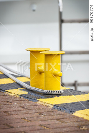Thick rope and yellow bollards on wharf using for anchorage of yachts Thick rope and yellow bollards on wharf using for anchorage of yachts 90370774