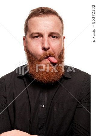 Portrait of a young, chubby, redheaded man in a black shirt making faces at the camera, isolated on a white background 90372332