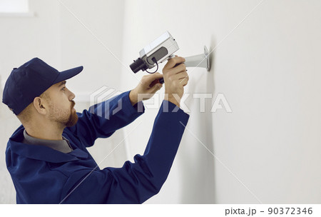 Professional male technician repairs or installing cctv camera system on wall inside house. Professional male technician repairs or installing cctv camera system on wall inside house. 90372346
