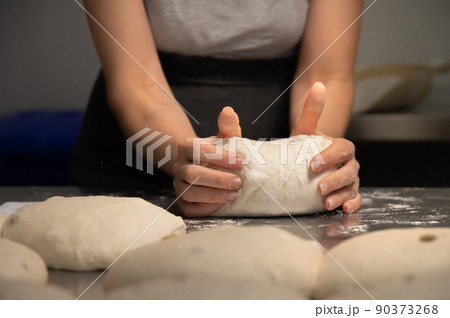 Women's hands carry out actions with raw bread. Dough before dipping into a bakery oven 90373268