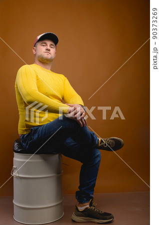 Portrait of an attractive friendly Caucasian man in a cap and yellow sweater on a brown background. Nice middle aged guy in casual clothes. Looks into the camera. Copy space 90373269
