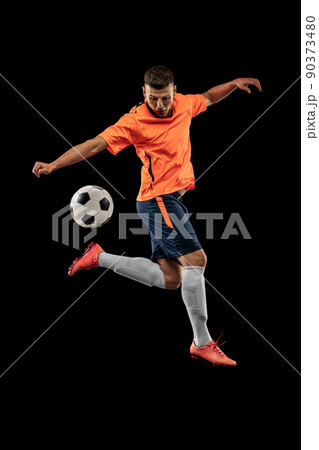 Studio shot of professional male football soccer player in motion isolated on dark background. Concept of sport, goals, competition, hobby, achievements 90373480