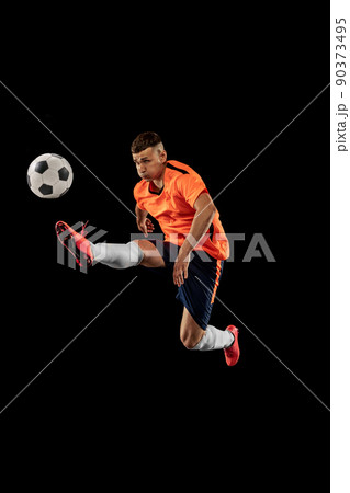 Studio shot of professional male football soccer player in motion isolated on dark background. Concept of sport, goals, competition, hobby, achievements Studio shot of professional male football soccer player in motion isolated on dark background. Concept of sport, goals, competition, hobby, achievements 90373495