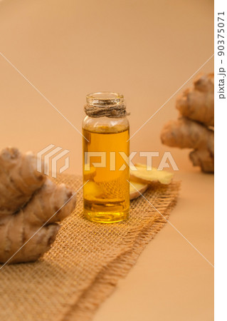 Glass bottle of essential ginger oil, ginger root on beige background. Healthy food eating concept. Zingiber officinale Essential oil. Natural cosmetics ingredients for skincare, body and hair care 90375071