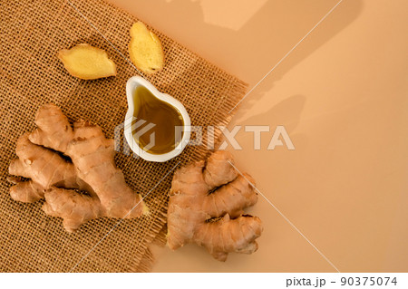 Sauce bowl of cooking ginger oil, ginger root on beige background. Healthy food eating concept. Zingiber officinale Natural cosmetics ingredients for skincare, body and hair care Sauce bowl of cooking ginger oil, ginger root on beige background. Healthy food eating concept. Zingiber officinale Natural cosmetics ingredients for skincare, body and hair care 90375074