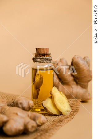 Glass bottle of essential ginger oil, ginger root on beige background. Healthy food eating concept. Zingiber officinale Essential oil. Natural cosmetics ingredients for skincare, body and hair care Glass bottle of essential ginger oil, ginger root on beige background. Healthy food eating concept. Zingiber officinale Essential oil. Natural cosmetics ingredients for skincare, body and hair care 90375075