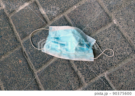 Dirty used medical mask on the walkway. Protection against Covid-19. A measure to prevent the spread of the coronavirus. Dirty used medical mask on the walkway. Protection against Covid-19. A measure to prevent the spread of the coronavirus. 90375600