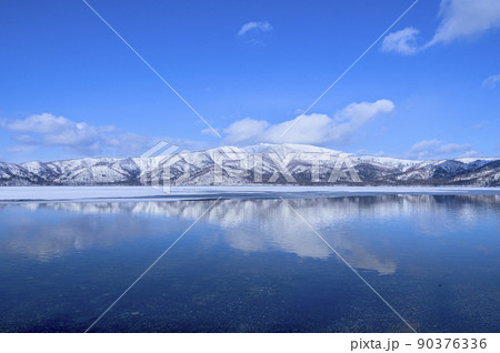 青空と雪山を湖面に映す冬の湖 90376336