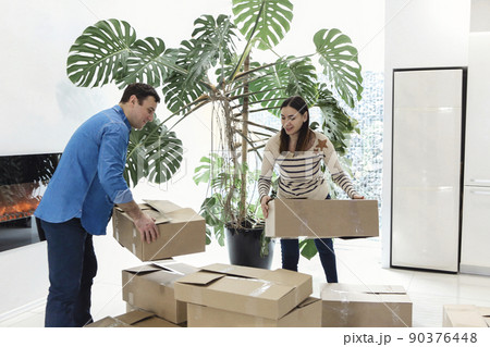 Happy couple with cardboard boxes in new home. Woman holding keys. 90376448