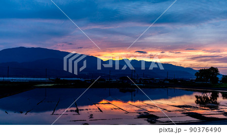 田植え直前の櫛形山の夕焼け、水田の映り込み 90376490