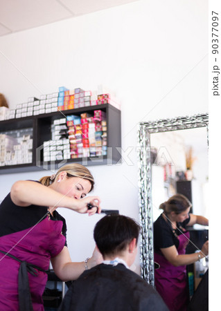 Hairdresser cutting and modelling brown hair by scissors and comb 90377097