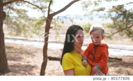 mom and son in the park. happy family a kid dream concept. mom holds baby son in her arms in a forest park close-up. baby and parent woman happy family walking in nature fun 90377806