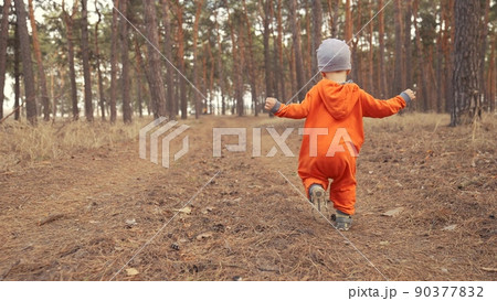 baby run. little boy in orange jumpsuit a walk through the forest park. kid dream happy family concept. baby run in fun the park. happy childhood carefree family walk child in the park 90377832