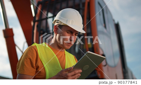 worker in hard a hat with digital tablet near excavator. construction site driver with online digital business tablet. industry construction concept. worker hard hat near excavator truck in uniform. 90377841