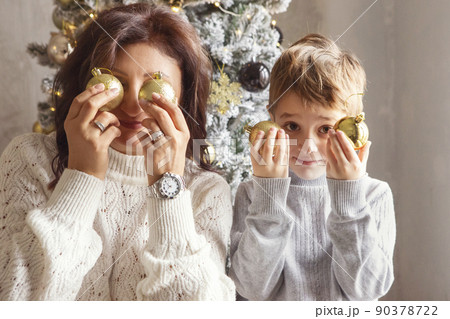 Christmas photo of happy family mother and little son holding xmas tree toy balls near face 90378722