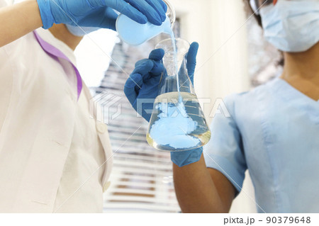 Two medical laboratory scientists wearing face masks working with test tubes in laboratory Two medical laboratory scientists wearing face masks working with test tubes in laboratory 90379648