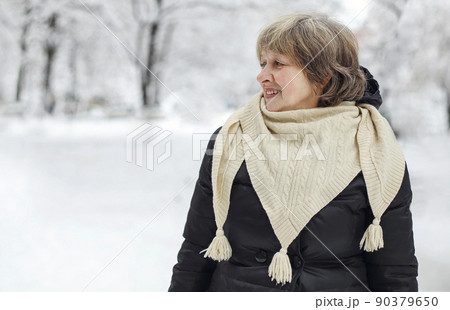Portrait of happy pleased with frosty snowy weather elderly woman in warm clothes smiling at camera 90379650