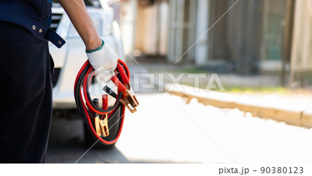 Focus car mechanic hand holding battery electricity cables jumper for charging car battery and repairing a broken car by connecting the battery, Services car engine machine concept 90380123