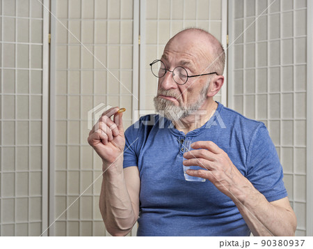 senior man is taking a medicine or supplement pill senior man is taking a medicine or supplement pill 90380937
