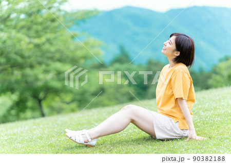 新緑の公園の芝生に座ってリフレッシュする若い女性 新緑の公園の芝生に座ってリフレッシュする若い女性 90382188