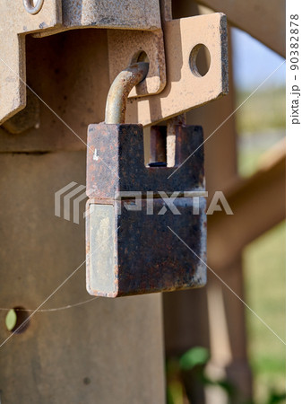 The gate is closed with a rusty padlock. Object security. 90382878