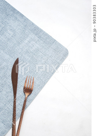 sliver cutlery fork and knife on a table mat on white  90383303