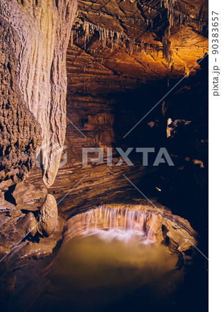 Rock formations in dark cave with underground waterfall 90383657