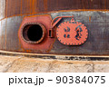 Opened rusty manhole on the fuel tank shell storage tank 90384075