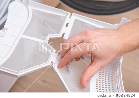 A man takes a lint filter out of dryer and cleans 90384924