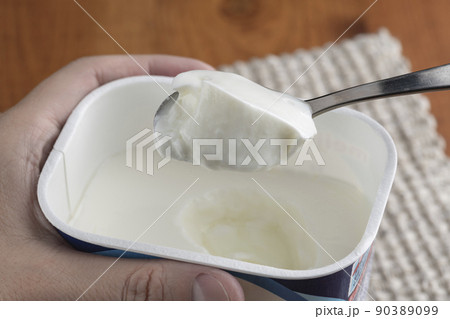 パック容器のプレーンヨーグルトをスプーンで掬って食べる 90389099