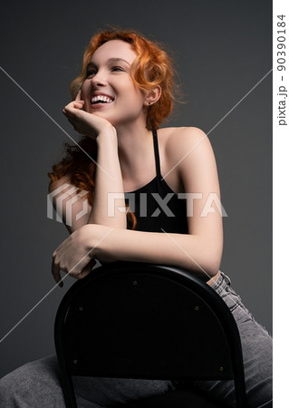 Delighted young lady sitting on chair leaning on hand and smiling 90390184
