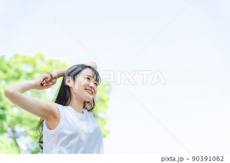 新緑の中でストレッチをする女性（健康・肩） 90391062
