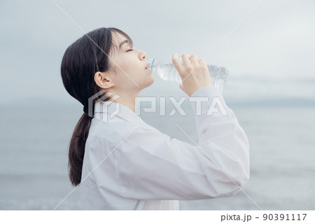 海辺で水を飲む女子高生 90391117