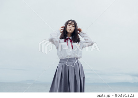海辺で音楽を聞くセーラー服を着た女子高生 海辺で音楽を聞くセーラー服を着た女子高生 90391322