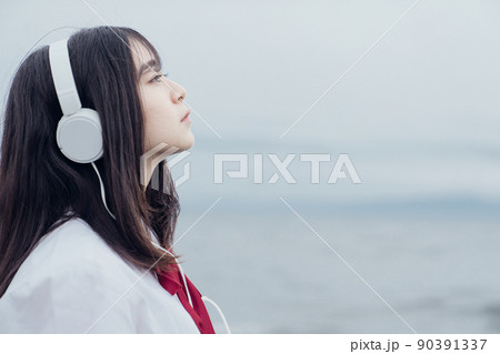海辺で音楽を聞くセーラー服を着た女子高生 海辺で音楽を聞くセーラー服を着た女子高生 90391337
